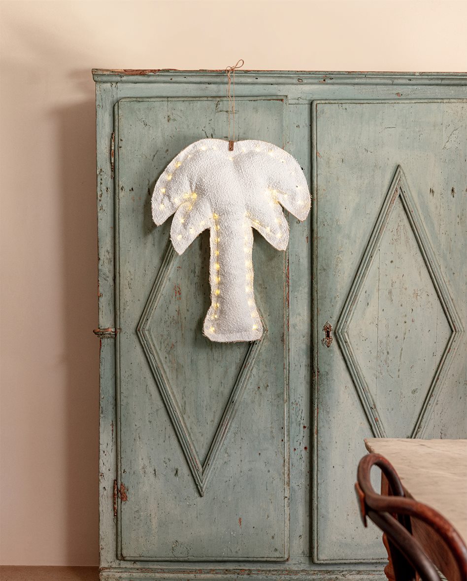Palmier lumineux en tissu bouclette suspendu à une porte ancienne